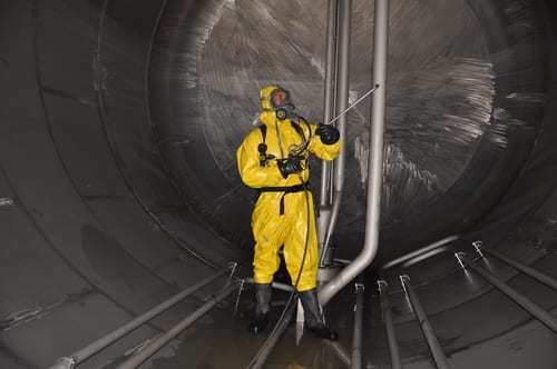 man in chemical suit inside of cargo tank on chemical tanker for cleaning operation