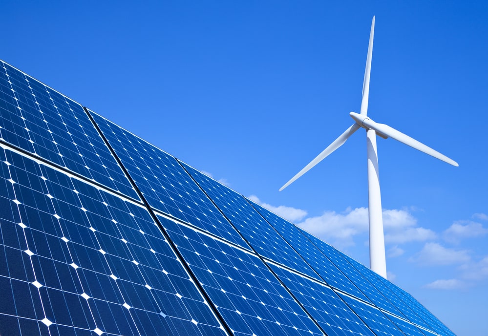 Windmill and solar panels in front of blue sky