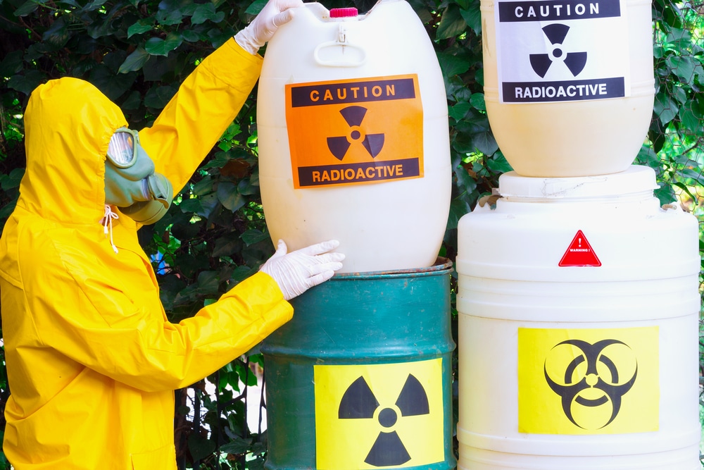 person in hazmat suit handling containers of hazardous waste